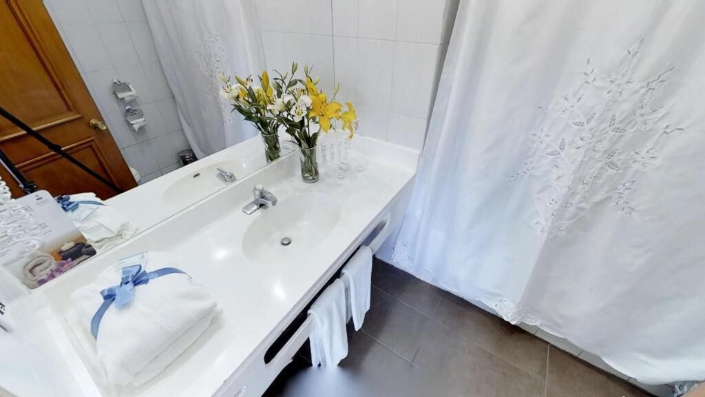 A bathroom with a white sink, mirror, and shower curtain.