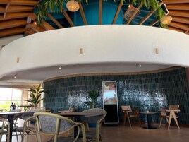 Un restaurante con techo curvo, sillas de mimbre, una pantalla vertical grande y vistas al exterior.