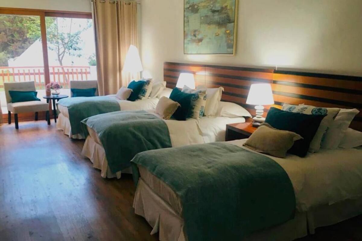 Une chambre d’hôtel avec deux lits, une petite table, des chaises et un balcon avec vue.