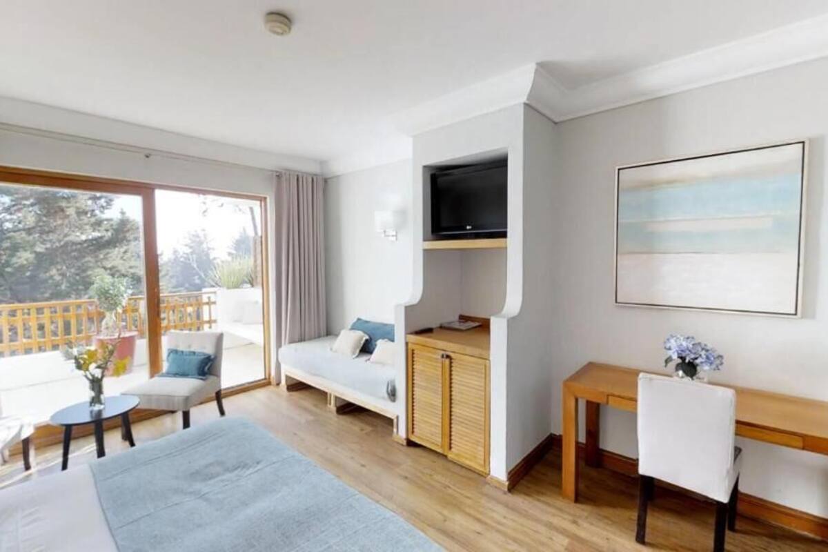 Un salon moderne avec un canapé, une petite table, un téléviseur fixé au mur et un balcon doté d’une balustrade en bois.
