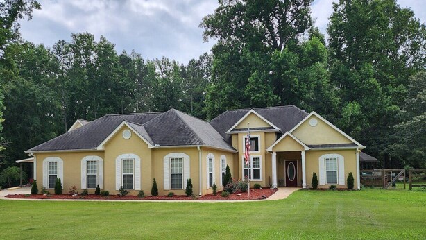 A two-story house with a yellow facade, a front porch, and a well-maintained lawn. - Poplar Meadow | King Bed • Gazebo • Pets Welcome! (Canton)