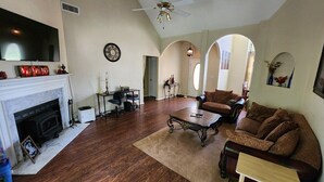 A spacious living room with a fireplace, a ceiling fan, and a large television. - Poplar Meadow | King Bed • Gazebo • Pets Welcome! (Canton)