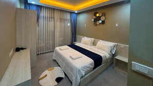 A modern bedroom with a bed, bedside tables, a headboard, a wall-mounted light fixture, and a decorative wall piece. - Room-luxury Boutique Pool Villa Ao Nang (Krabi)