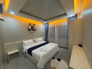 Habitación de hotel moderna con una cama grande, mesitas de noche, un espejo montado en la pared y una ventana con cortinas.