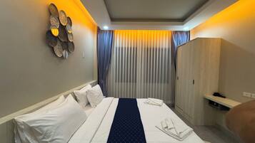Une chambre d’hôtel équipée d’un lit, d’une armoire, d’un miroir et d’un luminaire fixé au mur.