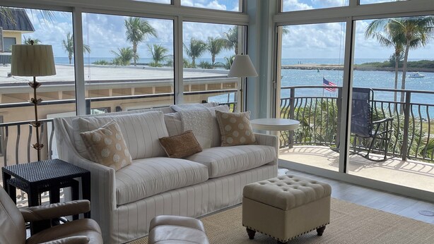 Ein geräumiges Wohnzimmer mit großem Fenster mit Blick auf Strand und Meer.