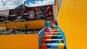 A colorful outdoor staircase leading to a building with a mural. - Hostal Capullo de seda (Zapatoca)