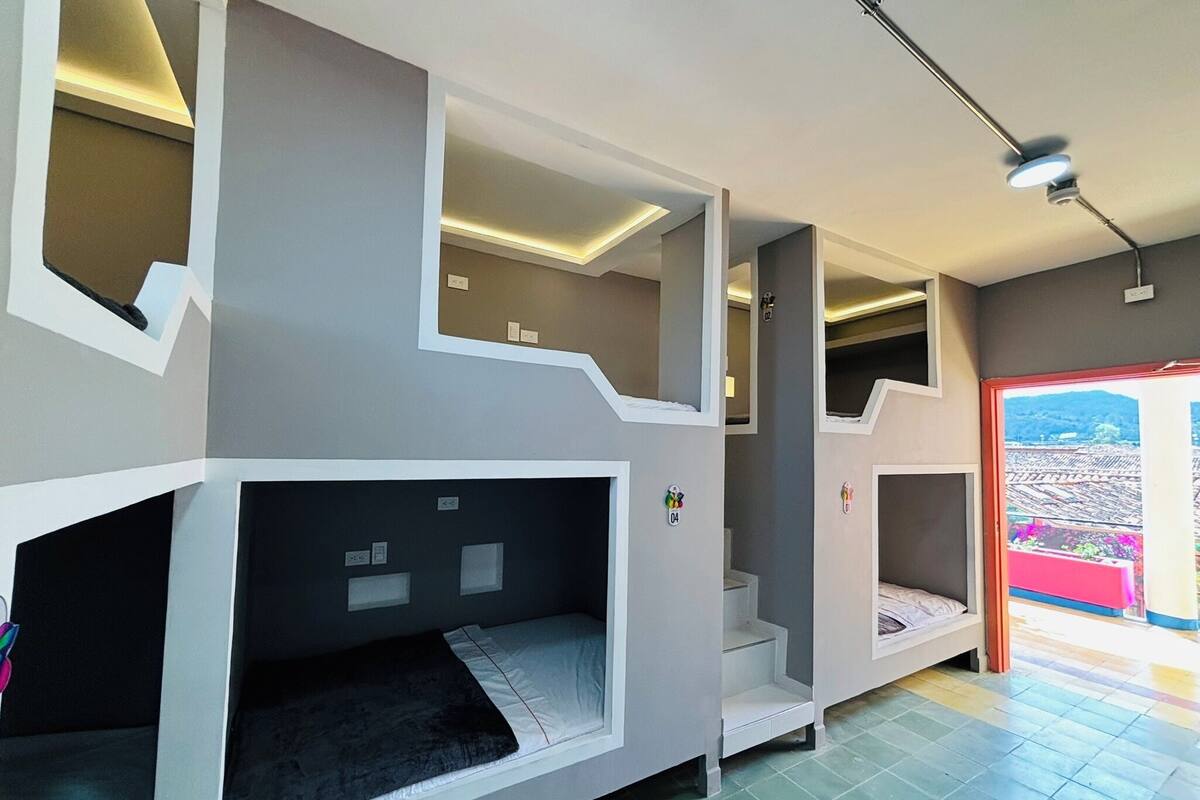 A modern interior with bunk beds, a staircase, and a view through an open door.