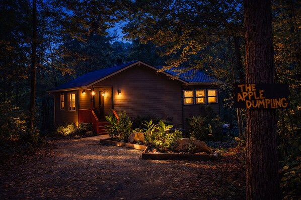 Une cabane rustique dotée d’un porche, d’une façade en bois et d’une enseigne sur laquelle on peut lire : « THE APPLE DUMPLING ».