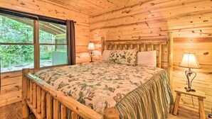 A wooden cabin room with a bed, a nightstand, and a window. - Bear Paw near Helen, Wineries & Hiking! (Clarkesville)