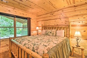 A wooden cabin room with a bed, a nightstand, and a window. - Bear Paw near Helen, Wineries & Hiking! (Clarkesville)
