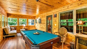 A pool table in a wooden cabin with a sofa and a chair, large windows, and a door. - Bear Paw near Helen, Wineries & Hiking! (Clarkesville)