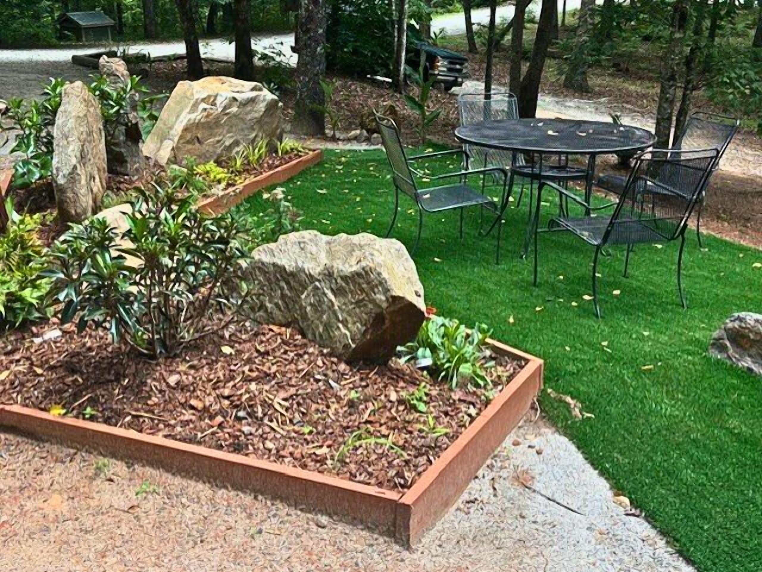 A garden area with raised planters, a round table, and chairs.