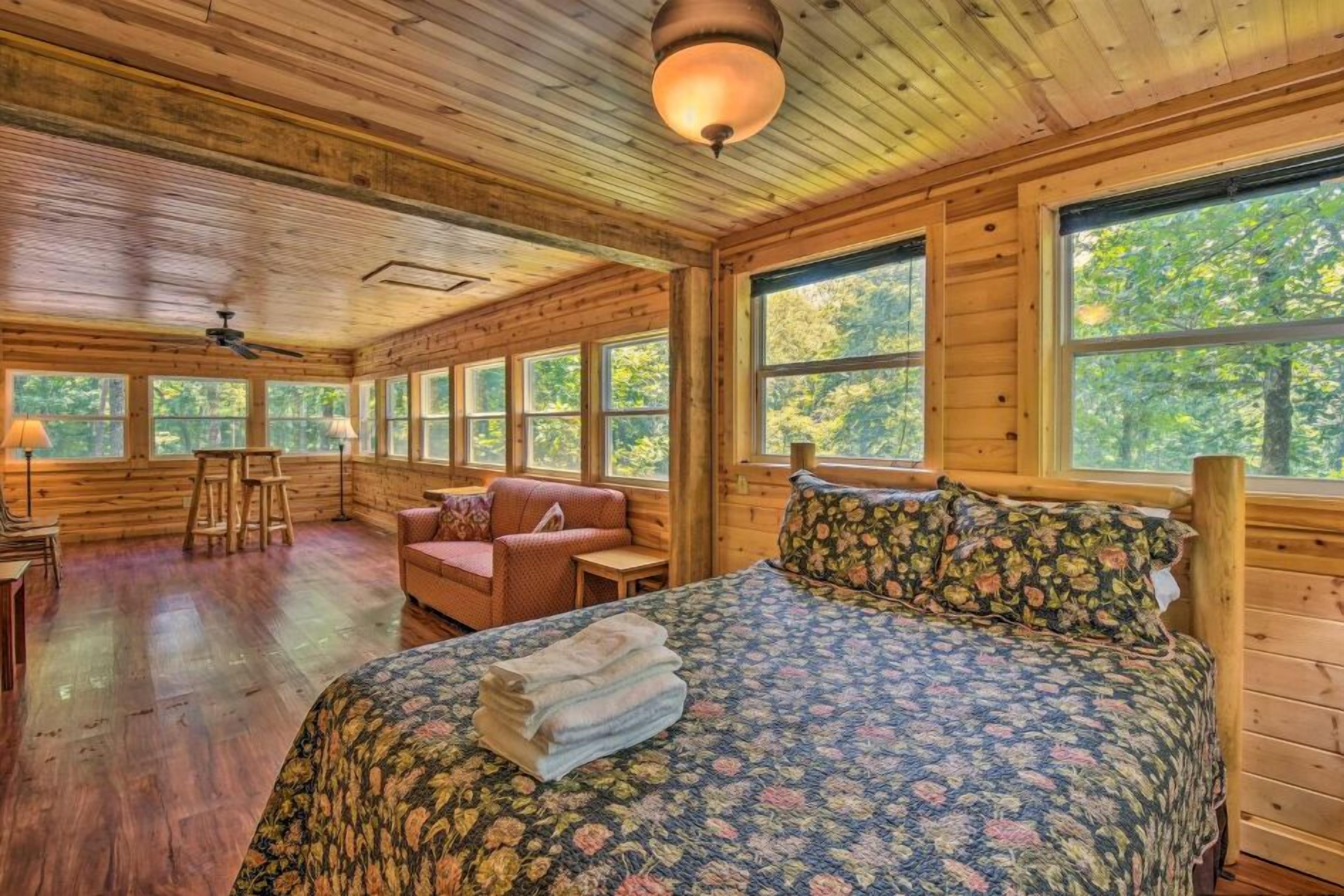 Une chambre aménagée dans un chalet en rondins, avec un lit, un canapé et un fauteuil.