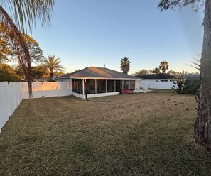 A house with a covered patio, a fenced yard, and palm trees. - 3-bedroom house in pleasant Palm Coast with cool AC (Palm Coast)
