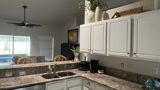 A kitchen with white cabinets, granite countertops, a built-in dishwasher, and a ceiling fan. - 3-bedroom house in pleasant Palm Coast with cool AC (Palm Coast)