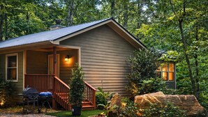 Eine Hütte mit Veranda, Grill und kleinem Garten.