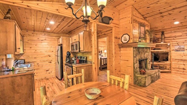Ein Holzinnenraum mit Esstisch, Stühlen, Kamin und Küchenzeile.