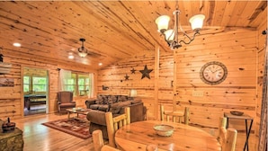 Ein Interieur einer Holzhütte mit Esstisch, Stühlen, einer Couch und einem Kamin.