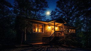 En træhytte med veranda, trappe og udsigt til nattehimlen.