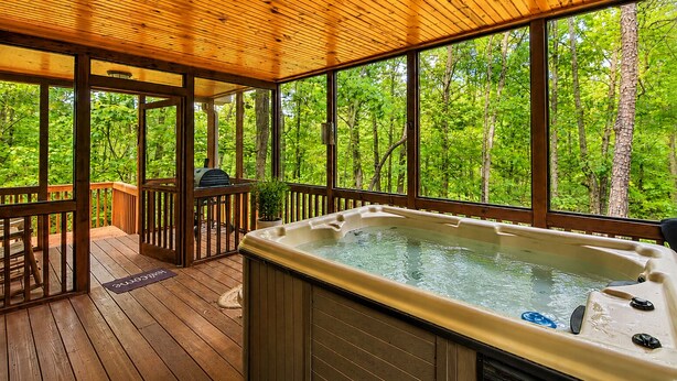 A hot tub on a wooden deck with a view of a forest.