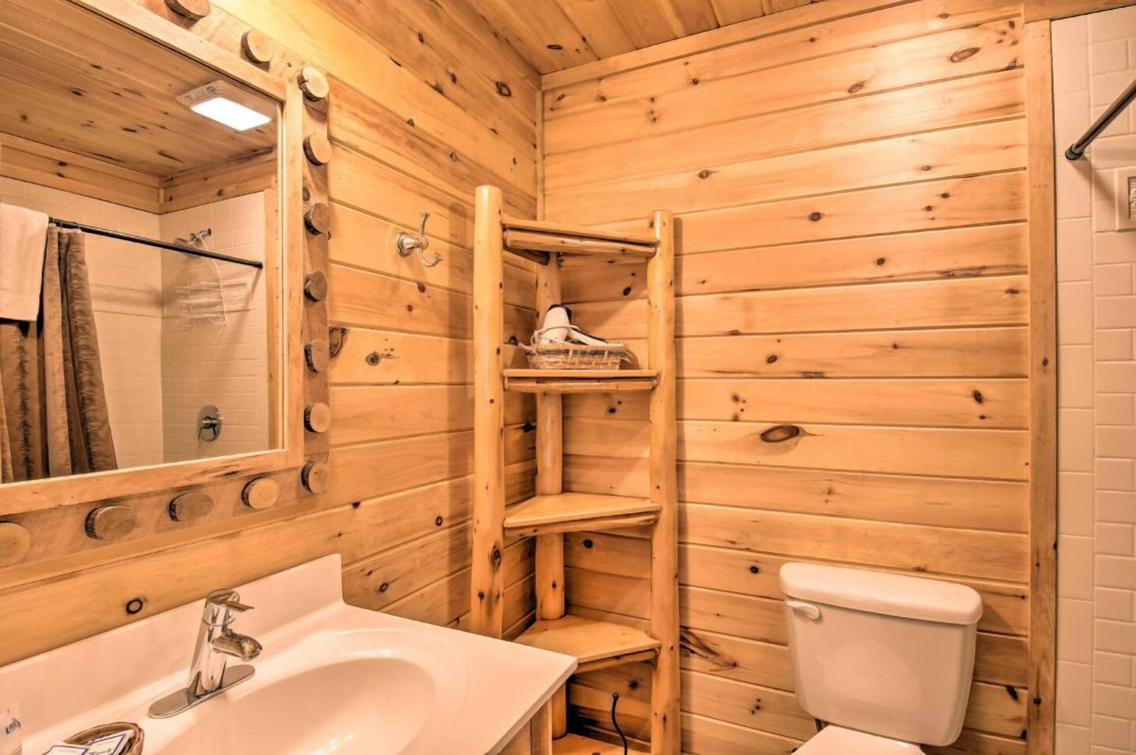 Puisesta mökistä löytyvä kylpyhuone, jossa on pesuallas, peili, wc ja hyllyt.