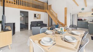 Ein großzügiges Loft-Apartment mit Essbereich für vier Personen, einer Küche mit modernen Geräten und einem Schlafzimmer im Loft-Stil mit einer Holztreppe.