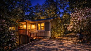 Eine Holzhütte mit Veranda, Treppe und Grill im Garten.