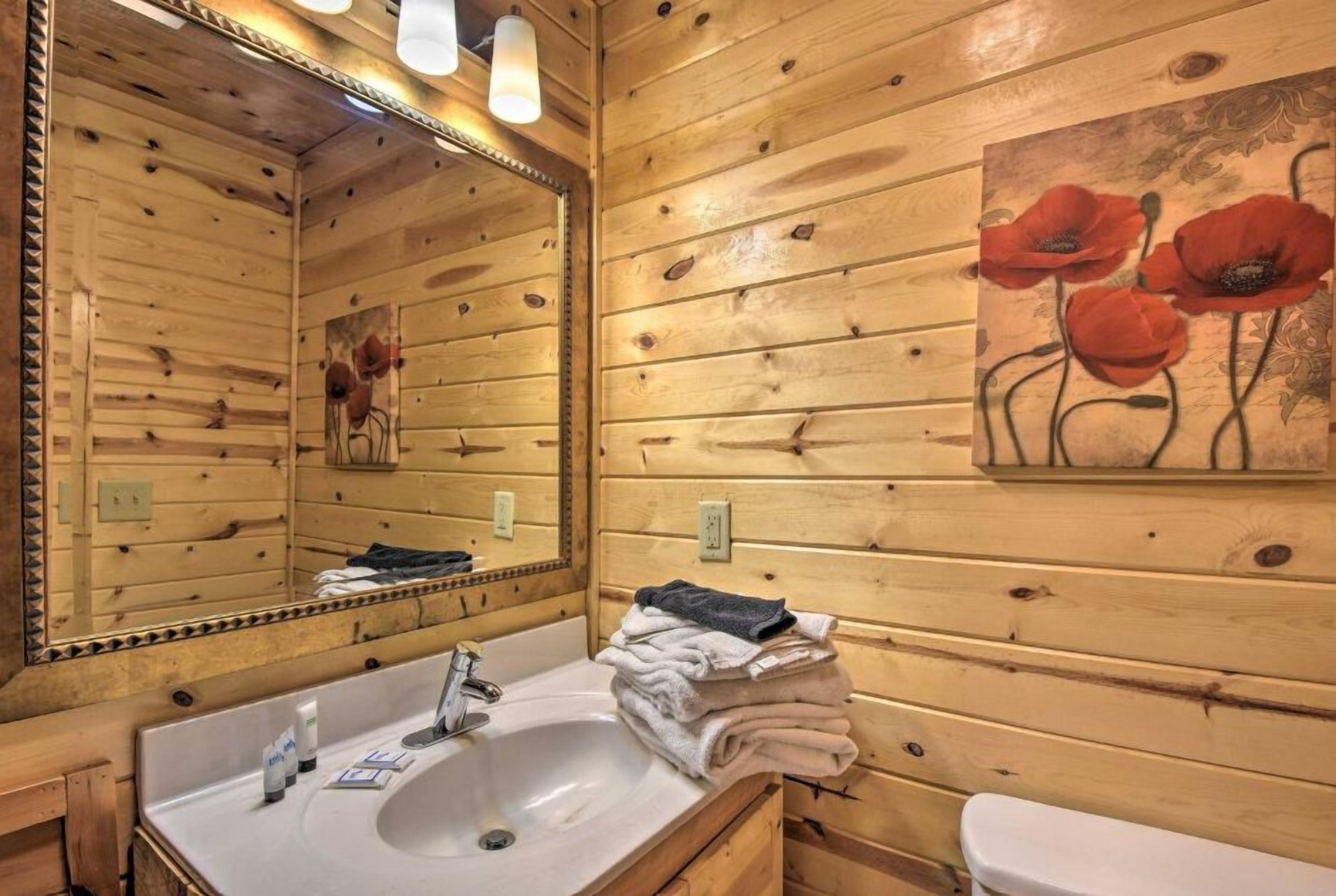 A wooden cabin bathroom with a sink, mirror, and toilet.