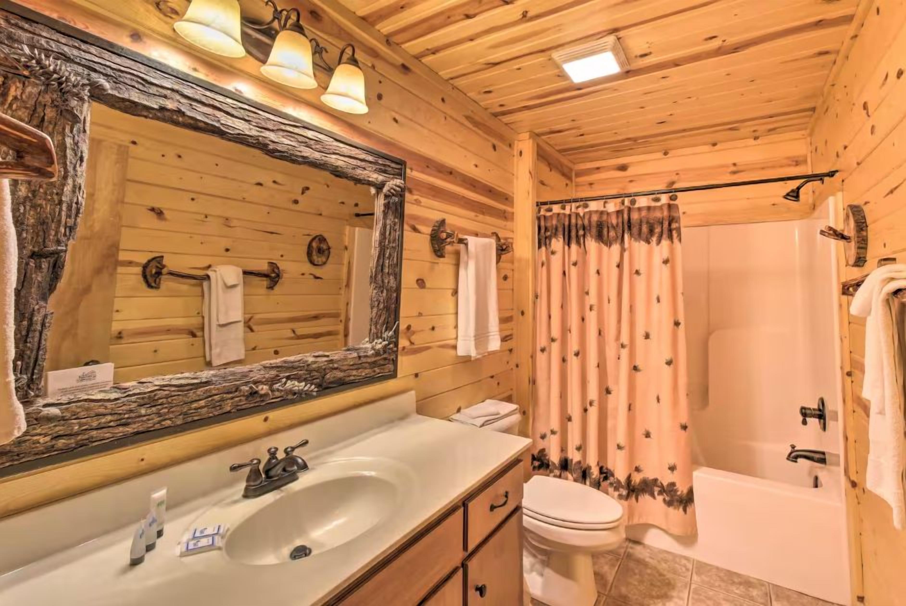 Un bagno in una baita di legno, con lavandino, wc e doccia.