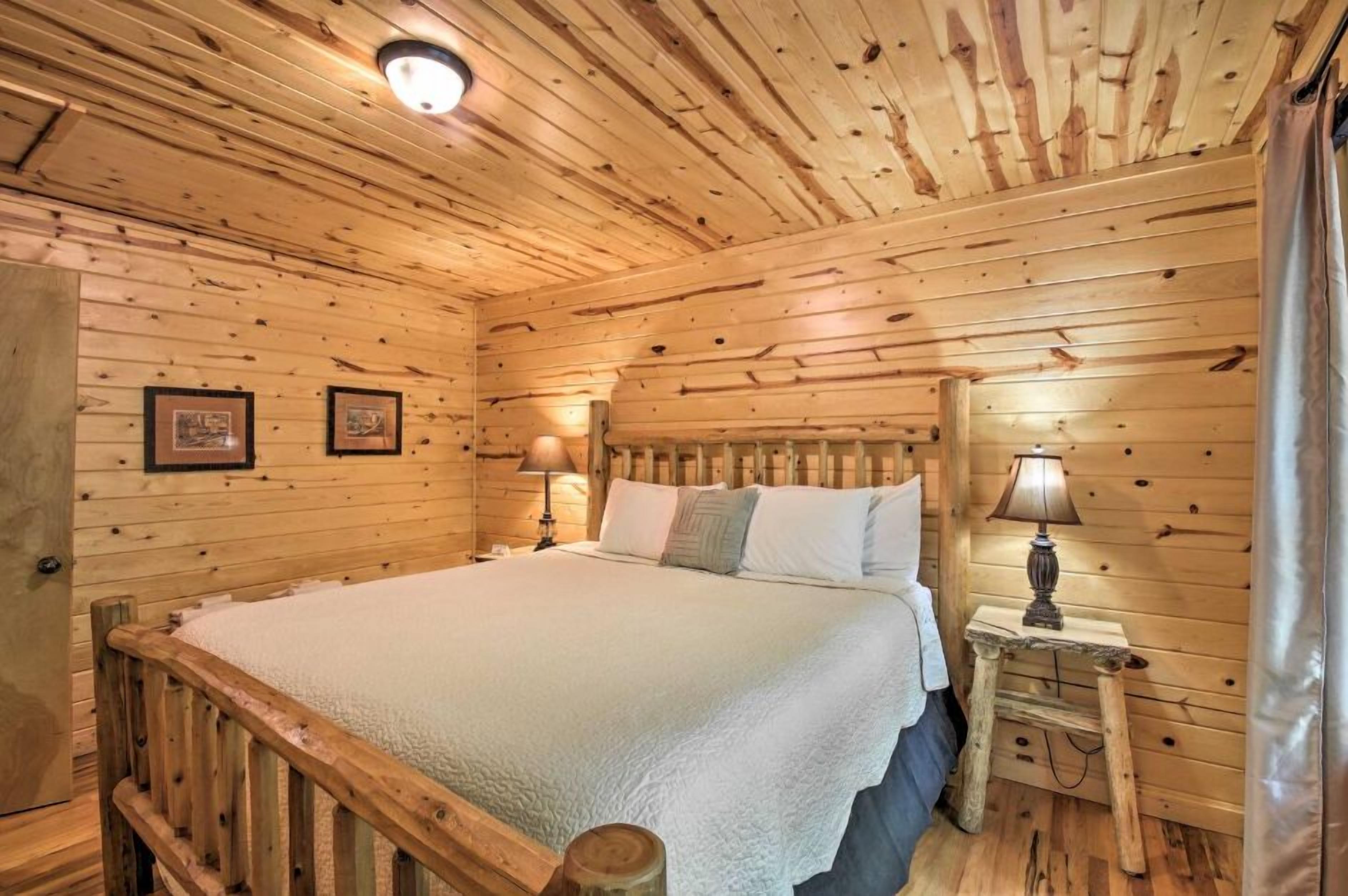 Un dormitorio de cabaña de madera con una cama, dos mesitas de noche con lámparas y un cabecero de madera.