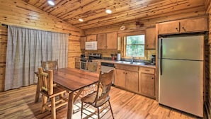 L’intérieur d’une cabane en bois comprend une table à manger, des chaises, un réfrigérateur, un four à micro-ondes et un évier.