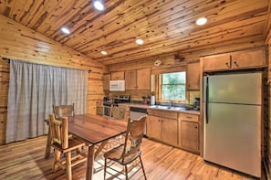 A wooden cabin interior with a dining table, chairs, a refrigerator, a microwave, and a sink. - Ridgeline Cabin close to Helen, Hiking & Wineries! (Clarkesville)