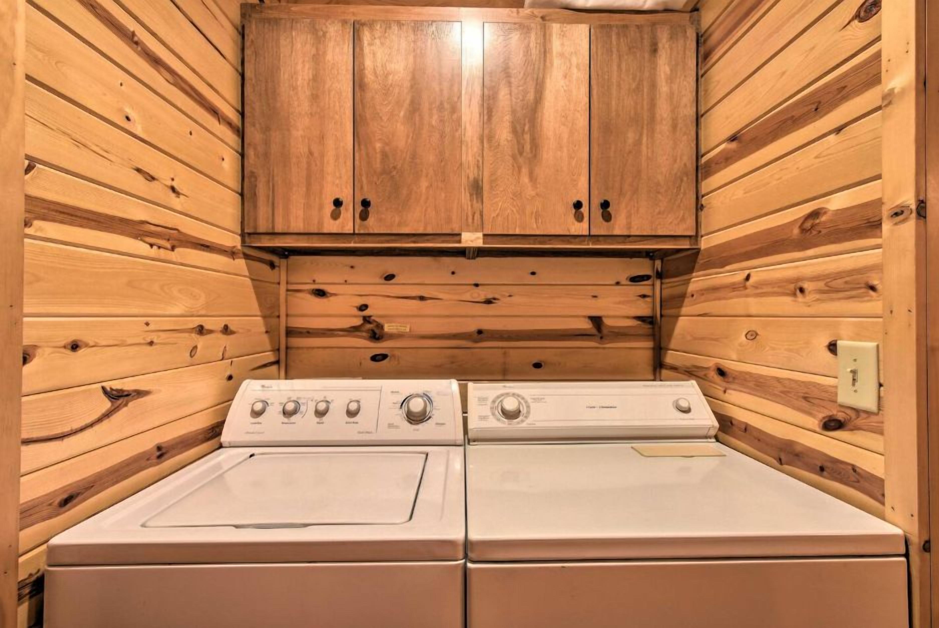 A laundry room with two stacked washers and a wooden cabinet above.