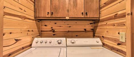 A laundry room with two stacked washers and a wooden cabinet above.