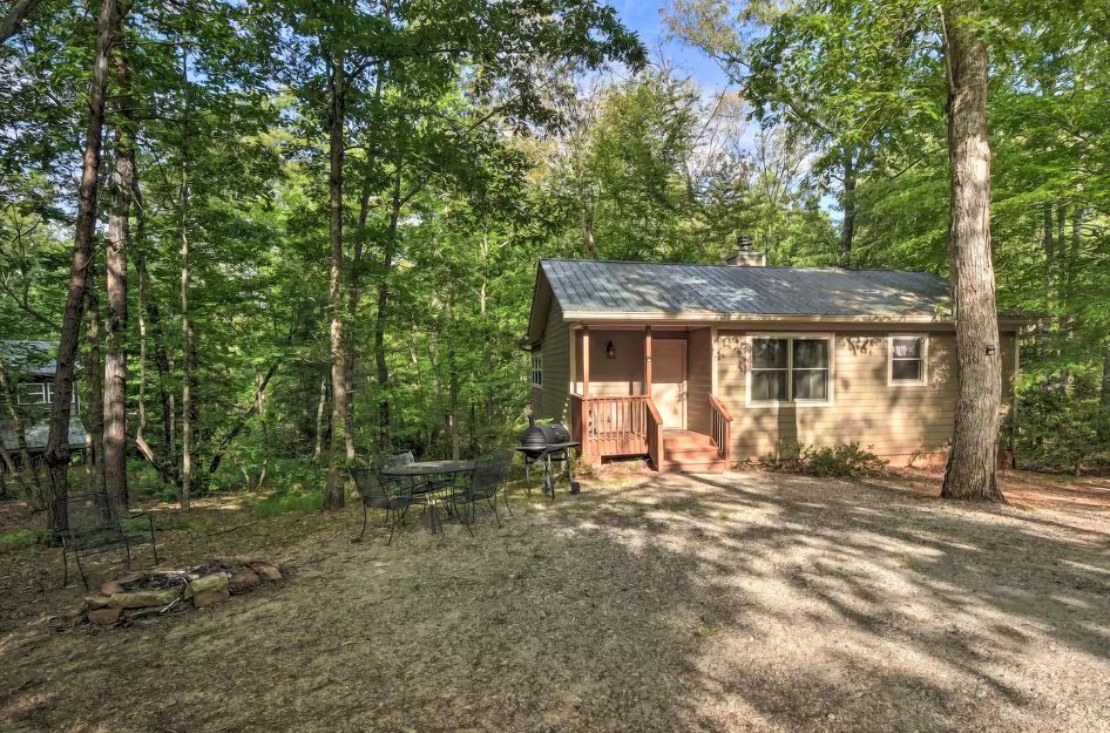 A small cabin with a porch, surrounded by trees.