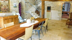 Un comedor rústico con una mesa y sillas de madera, una pared de piedra y una escalera que sube a un nivel superior.