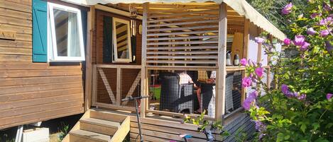 A wooden cabin with a covered porch, steps leading to a door, and a bicycle parked outside.