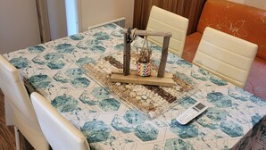 Un coin repas avec une table dressée pour deux personnes, un élément décoratif au centre et une fenêtre donnant sur les arbres.