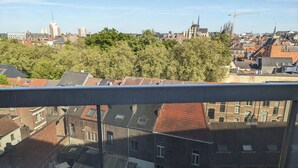 A cityscape with a mix of residential and commercial buildings, a prominent church, and a construction crane in the distance. - Stylish apartment with AC and sweeping views over historic Leuven (Leuven)
