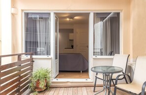Een balkon met een bed, een kitchenette en een zithoek met een tafel en stoelen.