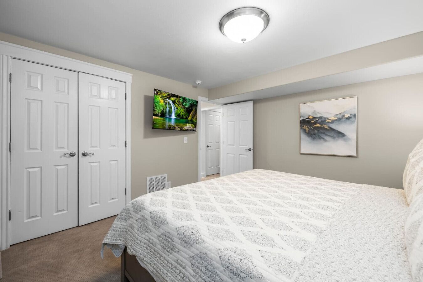 A bedroom with a bed, a TV, and two doors.