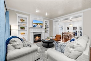 A living room with a fireplace, a dining area, and a view of the outdoors. - Mega Hot Tub - Fire Pit - Play Room - Sleeps 12 (Herriman)