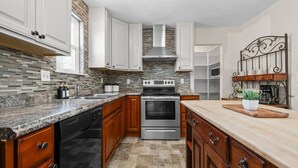 A modern kitchen with granite countertops, stainless steel appliances, and wooden cabinets. - Cozy Orem House | Playground | Game Rm | Bunk Rm (Orem)