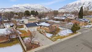A residential area with houses, a paved road, and snow-covered mountains in the background. - Cozy Orem House | Playground | Game Rm | Bunk Rm (Orem)