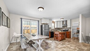 A spacious kitchen with a large island, white cabinetry, and a stone backsplash. - Cozy Orem House | Playground | Game Rm | Bunk Rm (Orem)