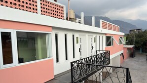 A building with a pink and white facade, multiple windows, and a staircase with a metal railing. - Naab Apart Complex (Panajachel)
