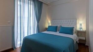 A bedroom with a large bed, a white headboard, and a bedside table with a lamp. - Apartment Seralya, Spacious Two Bedroom Apartment, Athens (Athens)