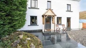 A modern house with a white exterior, a wooden front porch, and two wooden chairs. - Host & Stay | Morley House (Devon)