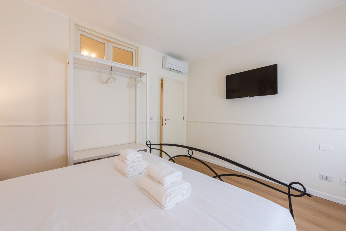 Een slaapkamer met een bed, een kledingkast, een televisie en een wandairconditioner.